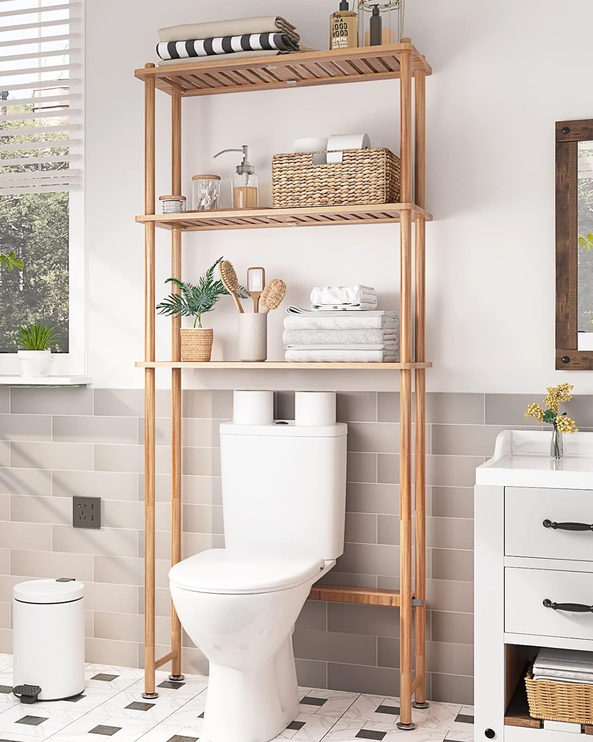 AmazerBath bamboo over-toilet shelf assembled and holding rolled towels, candles, and a plant